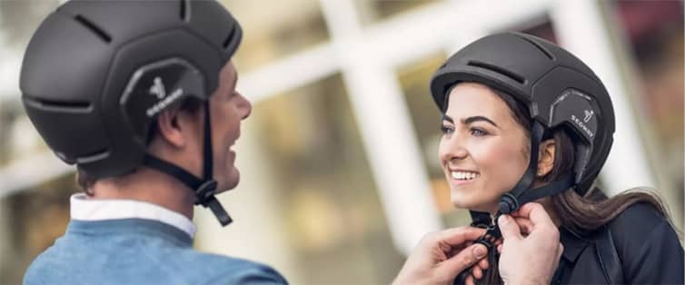 A man and a woman equipping themselves with Segway branded helmets.