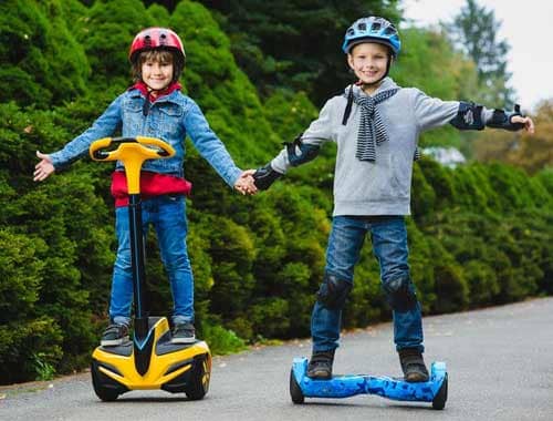 2 kids riding hoverboard with safety gear on